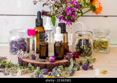 Lotto di diverse bottiglie di olio aromatherpy sul tavolo, decorate con fiori e piante selvatiche essiccate. Composizione stile di vita. Foto Stock