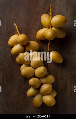 le date gialle fresche si isolano su sfondo di legno Foto Stock