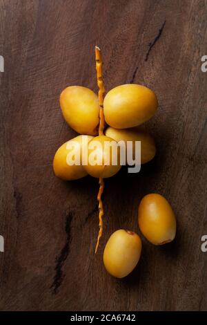 giallo fresco datteri frutta isolato su sfondo di legno Foto Stock