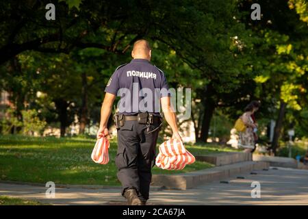 Sofia, Bulgaria. 3 agosto 2020. Poliziotto fuori servizio che porta borse con spuntini per i suoi colleghi mentre i manifestanti sono nelle strade di Sofia Bulgaria, mentre le proteste pacifiche contro la corruzione anti-governo si intensificano in tutto il paese per gli ultimi 26 giorni con alcune strade principali e intersezioni intorno al parlamento bloccato da tende e. le barricate e il centro della capitale sono completamente chiusi per i trasporti. Credit: Ognyan Yosifov / Alamy News Foto Stock