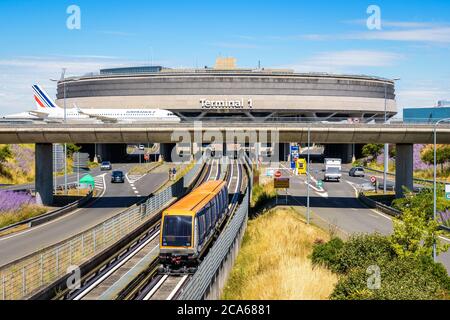 Il Terminal 1 dell'aeroporto di Parigi-Charles de Gaulle con un aereo di linea Air France che si svolge su un ponte di taxi sopra le strade e la linea di navetta per l'aeroporto. Foto Stock