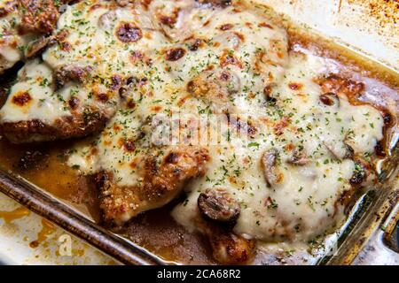 Cucina Italiana Pollo al forno Lombardia con sugo di funghi marsala condito con mozzarella fresca in casseruola di vetro Foto Stock