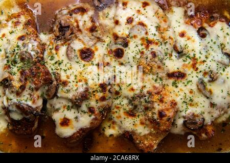 Cucina Italiana Pollo al forno Lombardia con sugo di funghi marsala condito con mozzarella fresca in casseruola di vetro Foto Stock