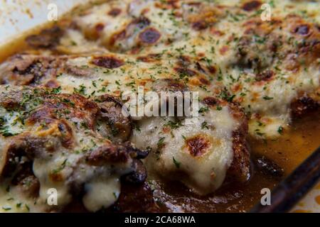 Cucina Italiana Pollo al forno Lombardia con sugo di funghi marsala condito con mozzarella fresca in casseruola di vetro Foto Stock