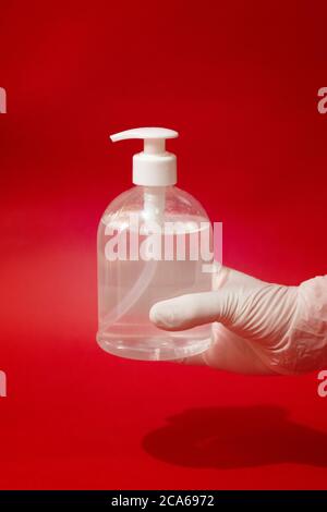 Igienizzatore manuale femminile in flacone di gel su sfondo rosso. Foto Stock
