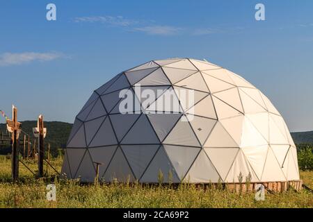 cupola geodetica bianca nella soleggiata giornata estiva sull'erba verde Foto Stock