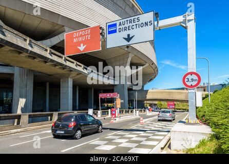 Le autovetture raggiungono l'edificio circolare del Terminal 1 dell'aeroporto di Parigi-Charles de Gaulle tramite la strada di accesso in una giornata di sole. Foto Stock