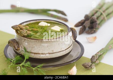 Zuppa cremosa di asparagi e asparagi verdi sullo sfondo. Cibo vegetariano sano. Foto Stock