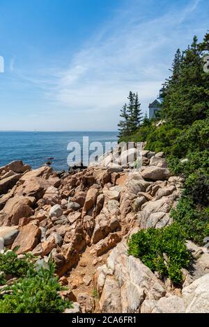 Aspra costa di granito roccia e lussureggianti alberi verdi presso il Faro di Bass Harbor nel Parco Nazionale di Acadia nel Maine, Foto Stock