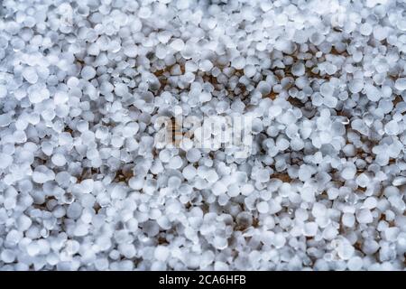 Vista ravvicinata sulle pietre di grandine sulla terrazza durante la tempesta di grandine dal cielo con luce solare Foto Stock