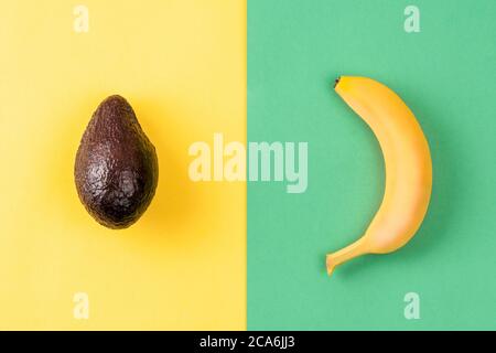 Layout creativo fatto di banana e avocado su sfondo colorato. Concetto estivo minimo. Frutta disegno. Foto Stock