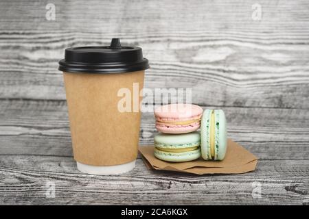 Una tazza di caffè da gustare e un delizioso macaron vicino su sfondo grigio in legno. Foto Stock