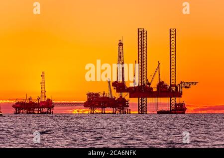 Il sole sorge dietro un carro di perforazione a gas naturale, il 20 aprile 2014, a Dauphin Island, Alabama. Foto Stock