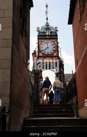 I turisti a Chester camminano attraverso la porta Eastgate verso il famoso orologio vittoriano Foto Stock