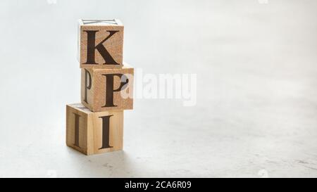 Pila con tre cubi di legno - lettere KPI che significa indicatore chiave di prestazione su di loro, spazio per più testo / immagini sul lato destro. Foto Stock