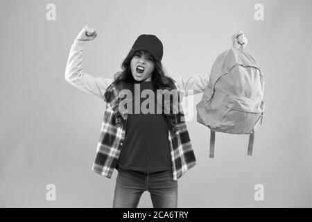 Potente bambino. Trasporto di oggetti in zaino. Scopri come montare correttamente lo zaino. Zaino per bambini alla moda ragazza. Utile accessorio di moda. Scolaretta rossa cappuccio capelli lunghi con zaino scuola. Foto Stock