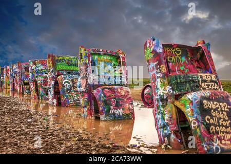 Cadillac Ranch con i suoi veicoli altamente verniciati nel mezzo di un campo fangoso appena fuori Amarillo, Texas Foto Stock