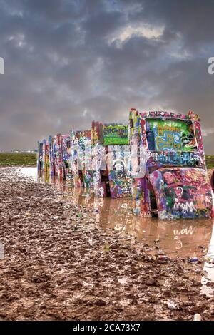 Cadillac Ranch con i suoi veicoli altamente verniciati nel mezzo di un campo fangoso appena fuori Amarillo, Texas Foto Stock