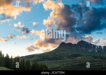 Spettacolari e colorate nuvole al tramonto su una vetta innevata delle San Juan Mountains del Colorado - scenario lungo la Million Dollar Highway nel Passo Molas Foto Stock