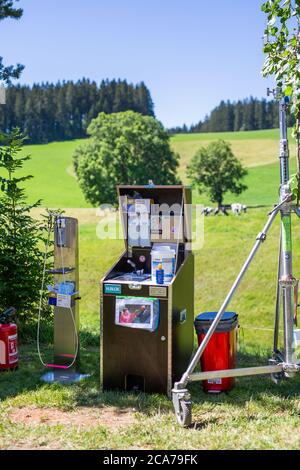 Furtwangen, Germania. 30 luglio 2020. Un distributore per disinfettante così come una stazione di lavaggio con rifiuti possono essere collocati in un set di pellicola, nelle mucche di fondo su un pascolo. La serie SWR "die Fallers - Die SWR Schwarzwaldserie" è stata trasmessa dal 1994 e conta oltre 1000 episodi ad oggi. La corona pandemia cambia e complica la sparatoria, in quanto deve essere osservato un rigoroso concetto di igiene. (A dpa ''i Fallers' si stanno mettendo in luce a causa di Corona') Credit: Philipp von Ditfurth/dpa/Alamy Live News Foto Stock