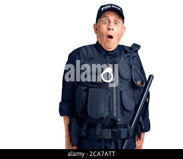 Uomo anziano bello che indossa uniforme della polizia spaventato e stupito con bocca aperta per sorpresa, faccia incredula Foto Stock