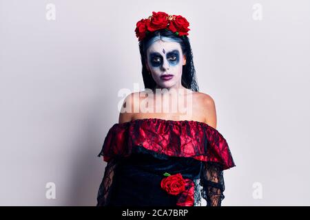 Giovane donna che indossa il giorno messicano del trucco morto guardando sonnolento e stanco, esausto per stanchezza e sbornia, occhi pigri al mattino. Foto Stock