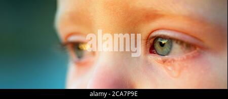 Piangi il bambino con gli occhi blu cielo, primo piano. Ragazzino tenero che piange. Caduta dell'occhio, goccia di strappo di piccolo capretto di innamorato. Il bambino emozionale perde la sua mamma. Infanzia Foto Stock