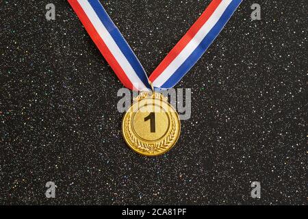 Medaglia d'oro 1 posto con un nastro su sfondo nero glitter. Concetto di vincita o successo, concetto di premio