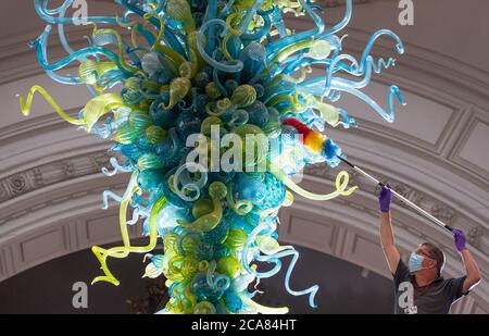 Il tecnico del Museo Andy Monk pulisce il lampadario in vetro Rotunda di 27 piedi di Dale Chihuly, che è composto da 1,300 elementi in vetro blu e verde, al Victoria and Albert Museum di Londra, mentre si prepara a riaprire al pubblico il 6 agosto. Foto Stock