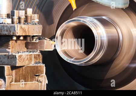 ruotando una parte raffreddata a olio su un tornio in primo piano, le parti rotanti sono sfocate in movimento Foto Stock