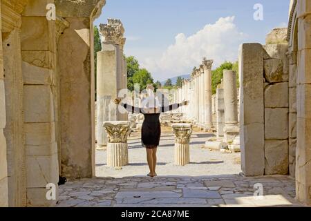 Bella giovane donna in abito nero nella città antica di Efeso Foto Stock