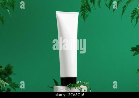 Contenitore senza marchio sul fronte dello shopping. Tubo in plastica per toilette. Foglie tropicali sullo sfondo. Flacon per cosmetici professionali. Spazio di copia. Prodotto ecologico Foto Stock