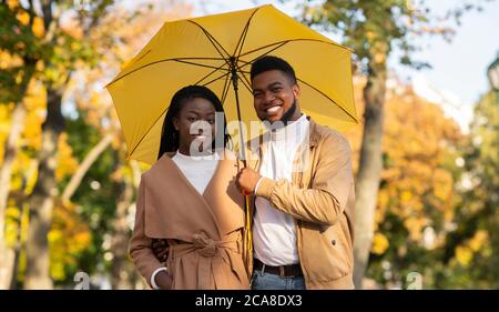 Ritratto di romantica coppia nera con ombrello nel parco autunnale Foto Stock