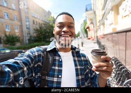 Eccitato afroamericano ragazzo prendendo selfie con caffè Foto Stock