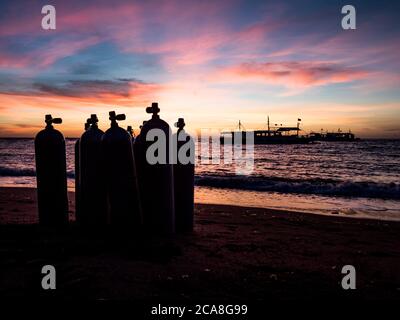 Alba sulla spiaggia nelle Filippine. Barche da immersione in attesa di subacquei al mattino presto. Silhouette di vasche da immersione in primo piano. Foto Stock