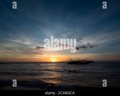 Incredibile alba sulla spiaggia delle Filippine. Barche da immersione in attesa di subacquei al mattino presto. Foto Stock