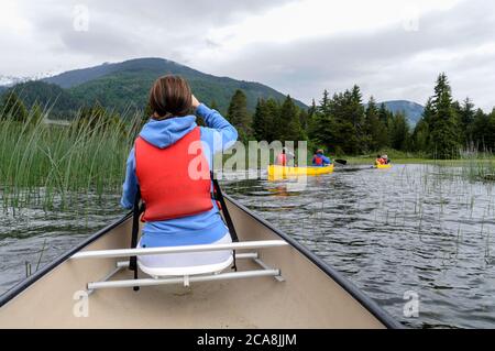 Un gruppo di turisti pagaiano i loro kayak sul lago alta per il fiume dei sogni d'oro a Whistler, British Columbia, Canada Foto Stock