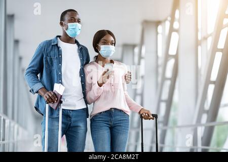 Coronavirus Viaggi. Coppia Africana americana che indossa maschere mediche protettive nel terminal aeroportuale Foto Stock