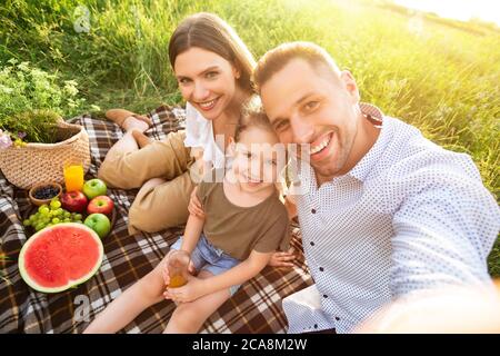 Felice famiglia che fa selfie seduto in campagna Foto Stock