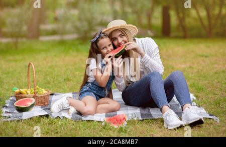 Mamma e figlia positivi mangiano il melone injoryng Summer Day fuori Foto Stock