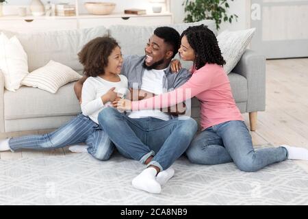 Passatempo di famiglia. Happy Black genitori giocare con la loro figlia piccola a casa Foto Stock