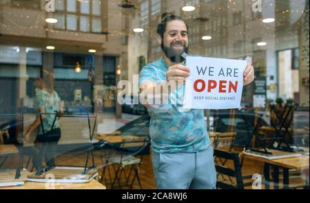 Uomo che posiziona il poster di apertura dopo il coronavirus Foto Stock