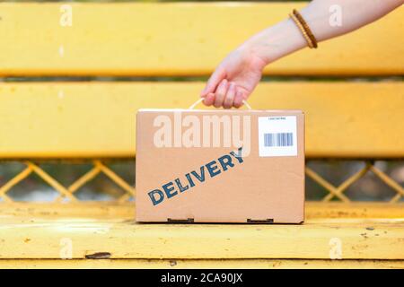 Il corriere mette una scatola di cartone con un codice a barre sul banco. Mano e pacco in primo piano. Il concetto di consegna espressa. Foto Stock