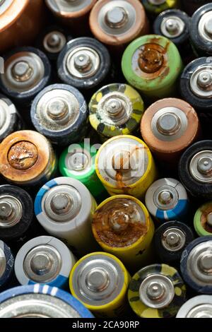 Primo piano delle estremità positive delle batterie scariche di diversi formati e dimensioni, messa a fuoco selettiva. Batteria usata con corrosione e ruggine. Pericolo gar Foto Stock