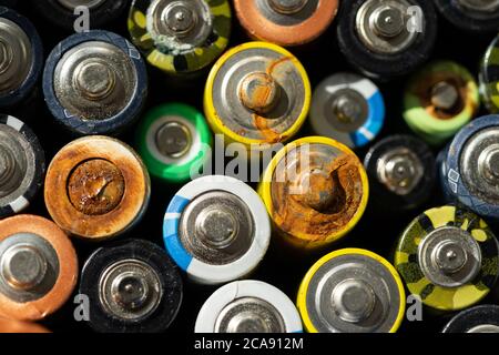 Primo piano delle estremità positive delle batterie scariche di diversi formati e dimensioni, messa a fuoco selettiva. Batteria usata con corrosione e ruggine. Foto Stock