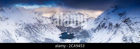 Panoramica aerea del Lago di Cavloc e boschi innevati, Valle di Bregaglia, Engadina, cantone di Graubunden, Svizzera, Europa Foto Stock