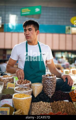 Un venditore a Zelenyy Bazar (bazar verde), un mercato agricolo con bancarelle che vendono carne, verdura e frutta secca, Almaty, Kazakistan Foto Stock