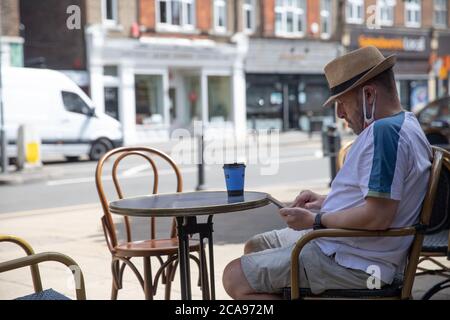 Oxted, UK, 5 AGOSTO 2020, UN uomo che si rilassa all'esterno di una caffetteria a Oxted godendo il caldo all'inizio dell'onda di calore che è previsto per i prossimi giorni.la temperatura oggi è 23C.Credit: Keith Larby/Alamy Live News Foto Stock