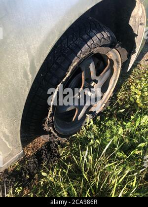 Distrutto soffiata fuori pneumatico con in esploso, shredded e gomma danneggiati su un suv moderna automobile. Appartamento a basso profilo pneumatico su di un cerchione in lega, strappato aperto in Foto Stock