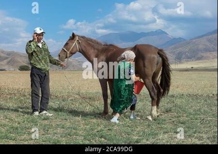 Uomo kazako con telefono cellulare e donna kazako che mungono un mare, il parco nazionale gabagly, Shymkent, Regione del Sud, Kazakistan, Asia Centrale, per uso editoriale Foto Stock